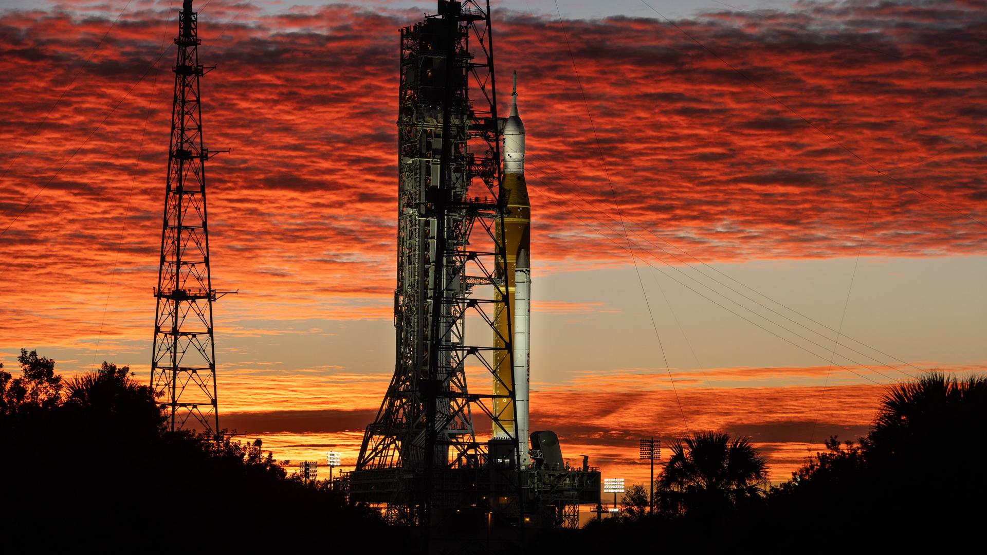 Artemis II on the launch pad with the sunrise behind it.