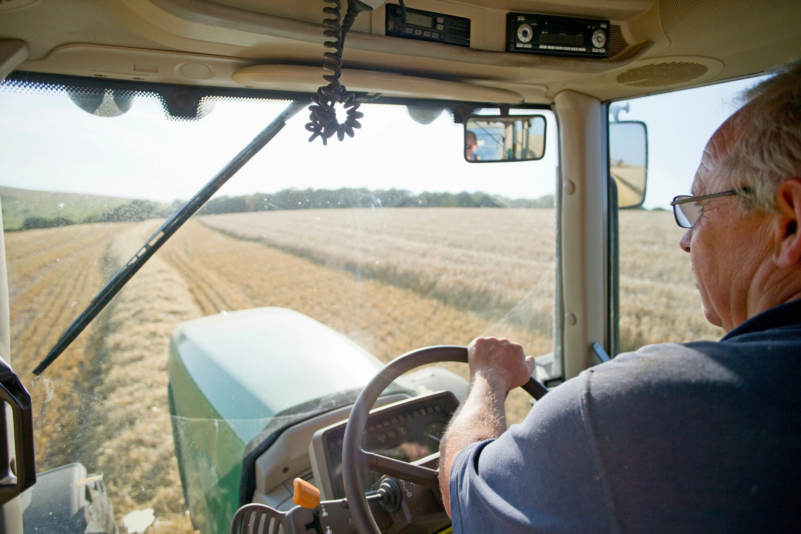 Farmer inside the cab of a tractor in a field.