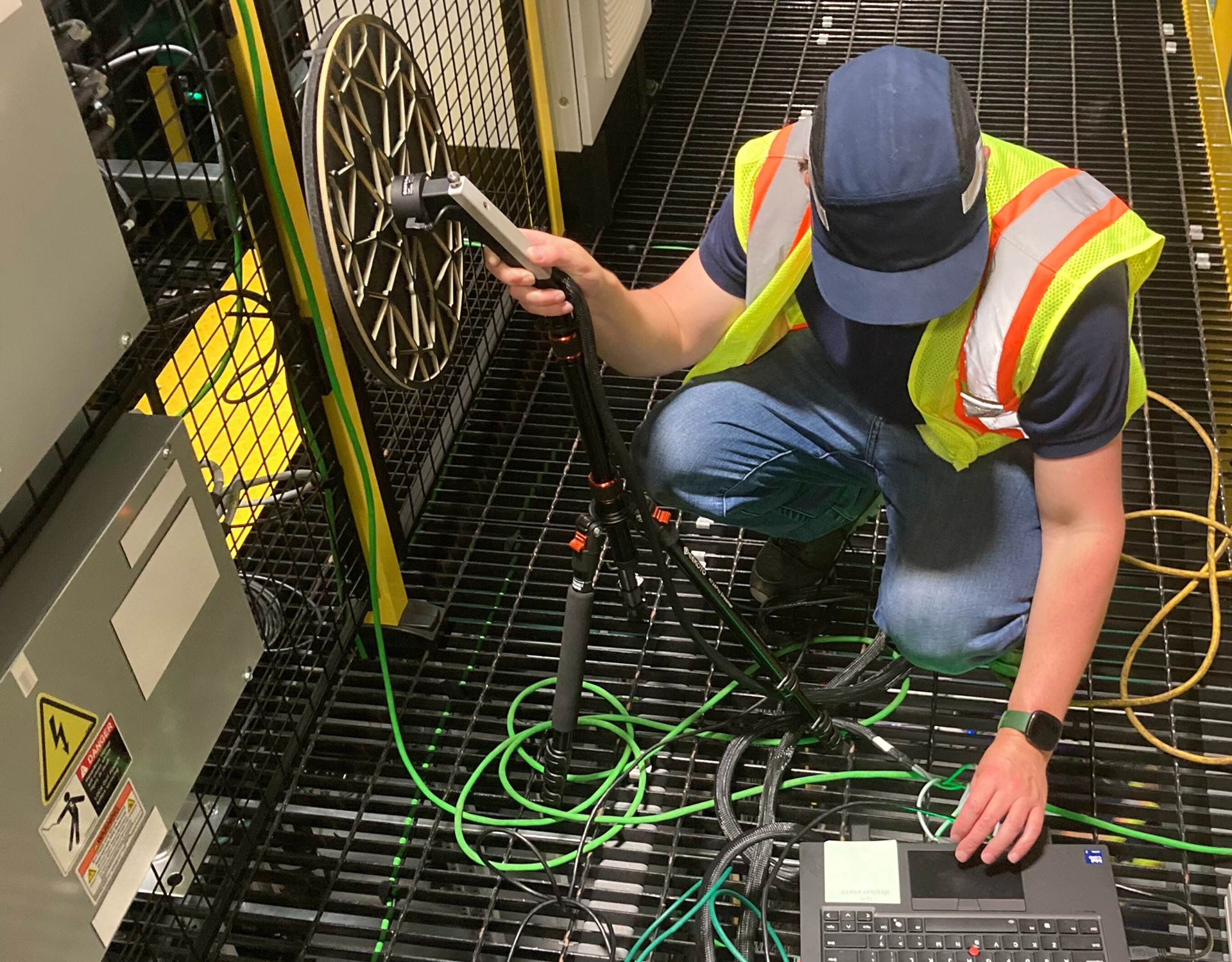 Soundcoat acoustic engineer using a sound camera in front of electrical machinery inside a fulfillment center